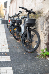 Black Electric Bicycles Leaning Against a Wall in the City During Autumn, Concept of Eco-Friendly Transportation