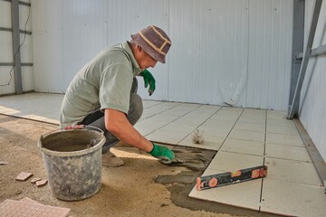 Worker laying tiles indoors.