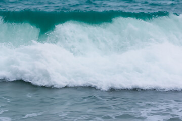 Fototapeta premium A surfer riding a wave in the ocean. Waves in the sea in nature. Sea waves nature water blue foam. Sea foam in the blue lifestyle water.