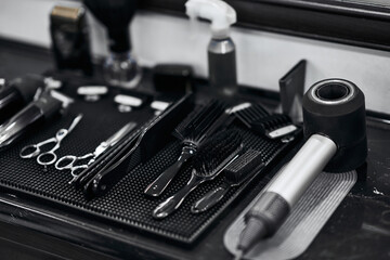 Naklejka premium Hair salon tools neatly arranged on a black countertop at a barbershop
