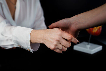Two Hands Engaging in a Firm Handshake Against a Dark Background