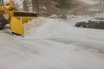 Yellow snowplow clears thick snow from street in snowstorm, helping maintain access for residents...
