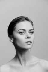 Fototapeta premium Young woman with a graceful pose, showcasing elegance and poise against a soft gray background. Capturing beauty and confidence through minimalistic composition.