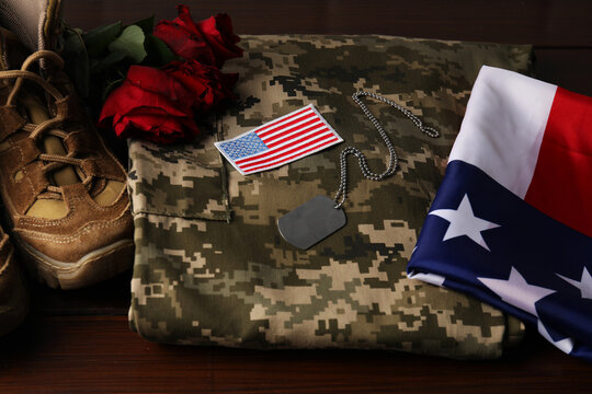 Veterans day. USA army patch, token, American flag, roses and military uniform on wooden table, closeup