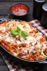 Delicious al forno pasta in baking dish on wooden table, closeup