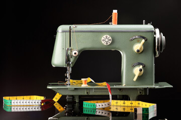 Professional sewing machine and measuring tape on black background