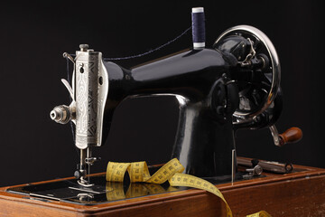 Professional sewing machine and measuring tape on black background, closeup