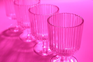 Empty glasses on pink background, closeup. Color tone effect