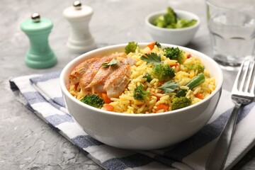 Tasty rice with vegetables and chicken served on grey table, closeup
