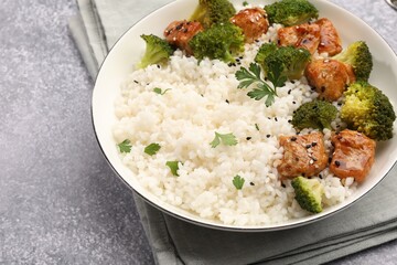 Tasty rice with broccoli, chicken and parsley on grey table, closeup