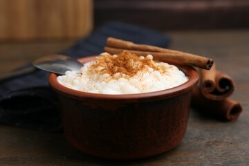 Delicious rice pudding with cinnamon sticks on wooden table, closeup