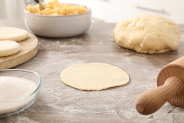 Making pirozhki (stuffed pastry pies). Pieces of dough on wooden table, closeup