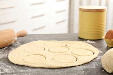 Making pirozhki (stuffed pastry pies). Raw dough and rolling pin on gray table indoors