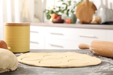 Making pirozhki (stuffed pastry pies). Raw dough and rolling pin on gray table indoors