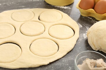 Making pirozhki (stuffed pastry pies). Raw dough and ingredients on gray table, closeup