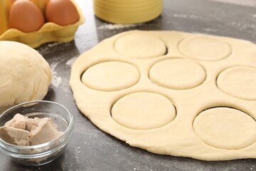 Making pirozhki (stuffed pastry pies). Raw dough and ingredients on gray table, closeup