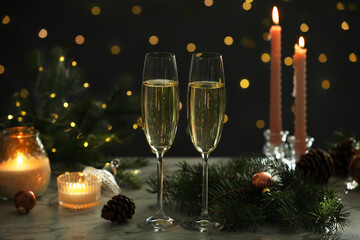 Delicious champagne in glasses and Christmas decor on marble table against blurred lights