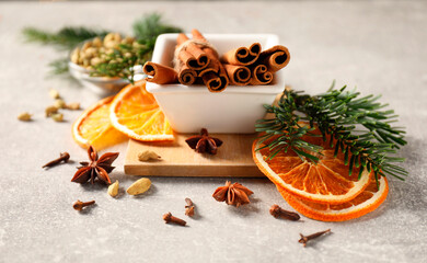 Different spices, dried orange slices and fir tree branches on light grey table, closeup. Christmas season