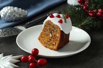 Piece of traditional classic Christmas cake and decor on gray textured table, closeup
