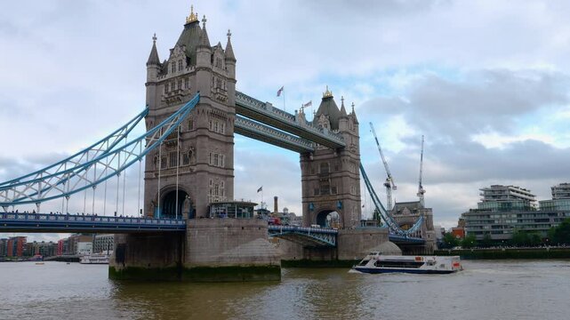 Experience the iconic scenery of London with this captivating stock footage. The clip captures boat traffic traveling under the majestic Tower Bridge on a cloudy day. 