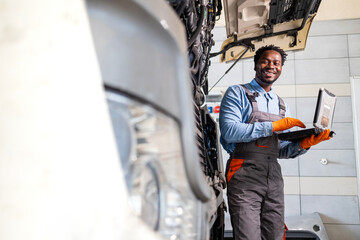 Smiling truck mechanic or serviceman checking engine cooling system of the vehicle.