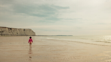 petite fille marchant seule au bord d'une plage vide
