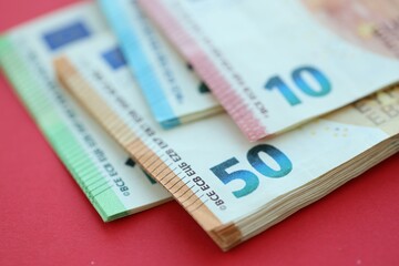 Big amount of one hundred, twenty, ten and fifty euro money bills on red background