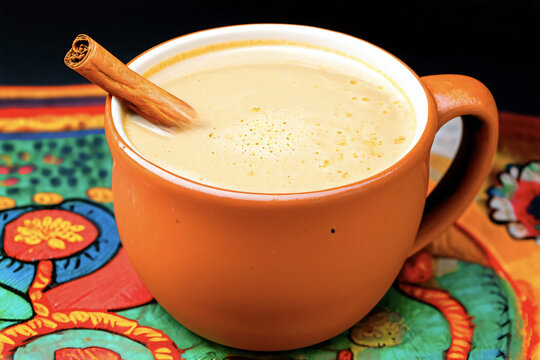 Traditional Mexican atole is served in a clay mug with a cinnamon stick