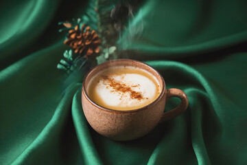 A steaming cup of Mexican Atole with a sprinkle of cinnamon, placed on a rich green background