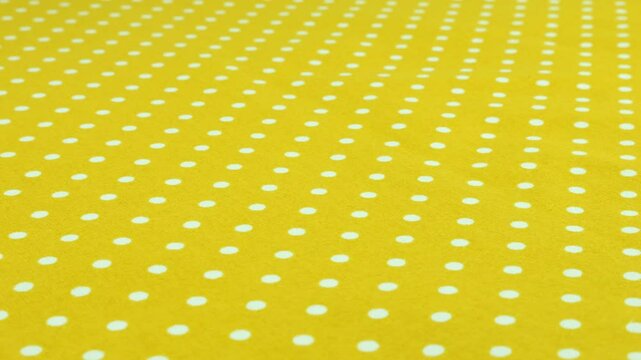 Close-up view of the safety yellow with white polka dots cotton fabric rotated on the display case. Textile background on the design theme, craft, handmade, patchwork, creativity theme.
