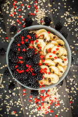 Oatmeal with red ripe blackberries and bananas in the bowl. Selective focus. Shot from above.