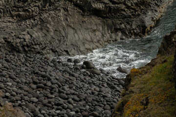 Powerful sea waves crash on black volcanic rocks with white foam in Iceland