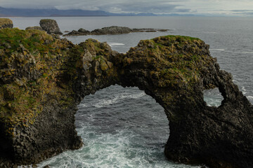 Fototapeta premium Aerial view of a lava rock arch in the sea off the coast of Iceland