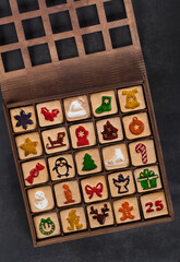 Advent cookies. 25 square Ginger cookies in the shape of a Christmas Advent Calendar. In a wooden gift box. Dark background. Top view