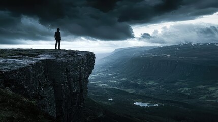 A solitary figure stands on the edge of a dramatic cliff overlooking a vast valley, surrounded by dark storm clouds and rugged mountain landscapes at dusk.