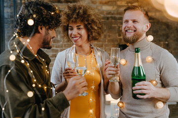 A group of friends raising glasses of champagne and one of them making a toast indoor