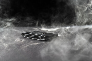 black leather wallet resting on a dark backdrop, surrounded by swirling smoke. Money appears to be burning, symbolizing fleeting wealth and the transient nature of material possessions