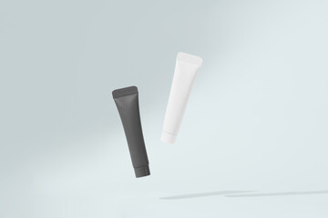 White and black mockup tubes levitating on blue isolated background with drop shadow. The concept of care cosmetics for the skin of the face, the presentation of beauty products
