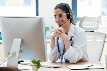 Female doctor explaining medical treatment to patient through a video call with laptop and...