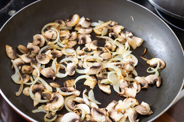 Champignons fried in a pan with olive oil and onions