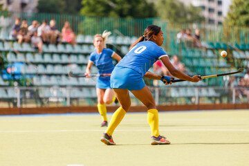 Young female player receiving the ball in field hockey match on a sunny day