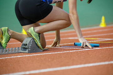 Runner preparing at starting blocks for a relay race during a track event