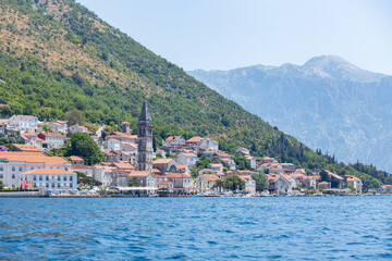 Fototapeta premium Coastal town nestled between mountains and water in summer sunlight