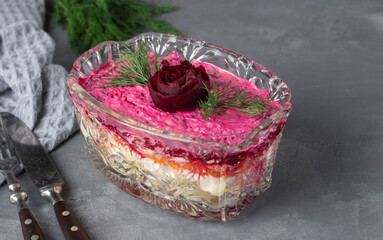 Traditional Russian holiday salad Herring under a fur coat decorated rose from beet in transparent salad bowl
