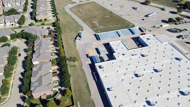 Residential neighborhood houses near extra large grocery store with container loading bay, commercial rooftop packaged units RTU on flat roof, HVAC conditioning cooling, heat pump air handlers