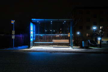 An empty Busstop at Night with a bench and lit roof