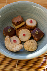 Various kinds of tasty Christmas chocolate, nuts and filled cookies in blue bowl