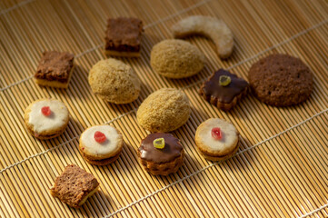 Various kinds of tasty Christmas chocolate, nuts and filled cookies on japanese wooden mat