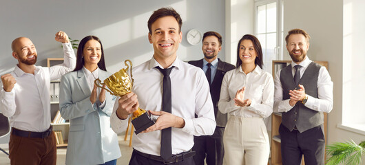 Portrait of a happy smiling young man winner holding the trophy award for success in business...