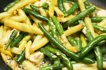 Fried yellow and green beans with olive oil and feta cheese. Shiny vegetables with rich flavor. Healthy and affordable dish idea. Perfect for a nutritious and delicious meal. Food lover paradise.